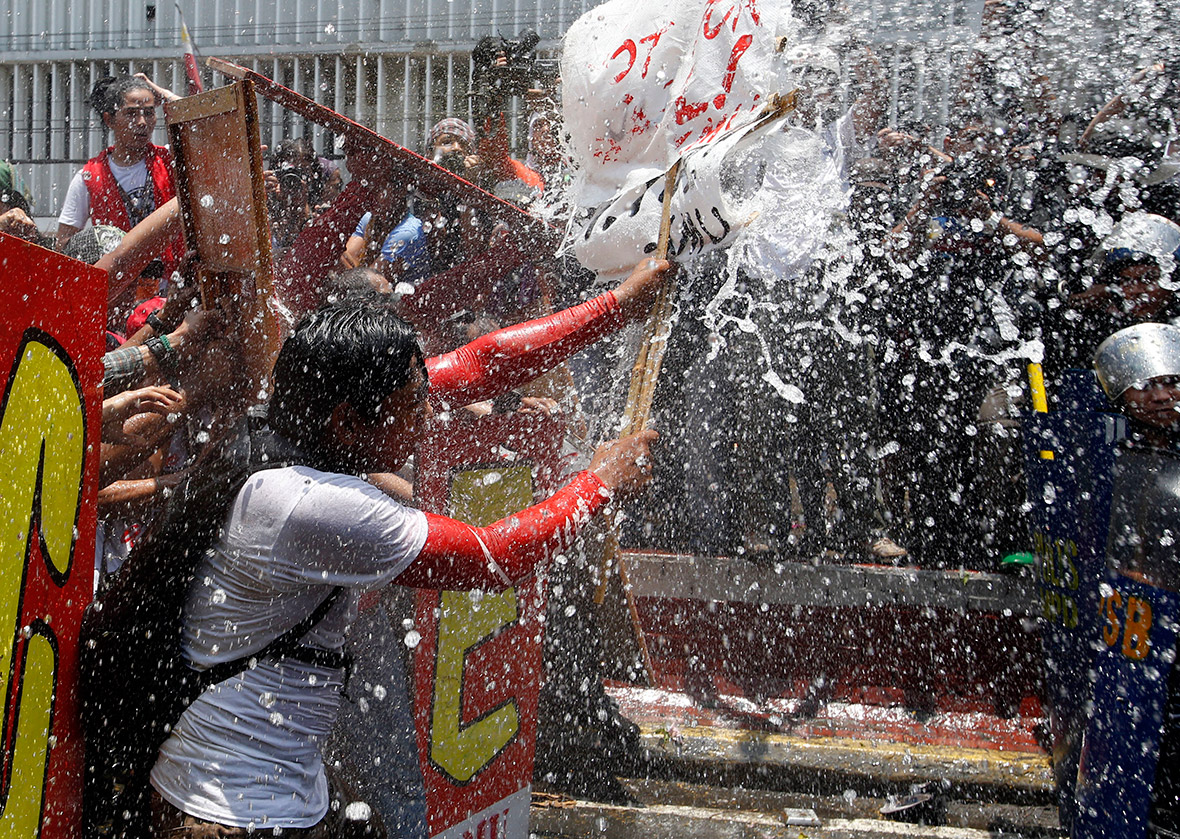 An activist uses a placard to protect herself from the blast of a water cannon.
