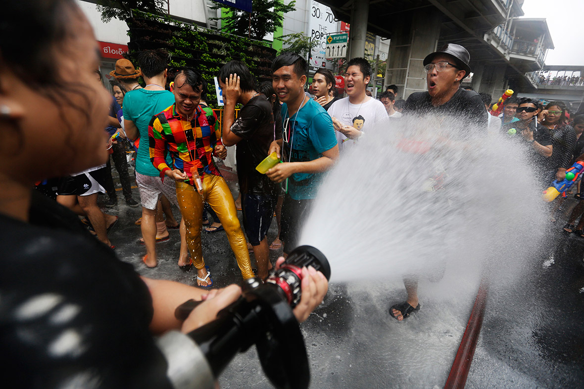 A woman blasts revellers with a firehose on Silom Road in Bangkok