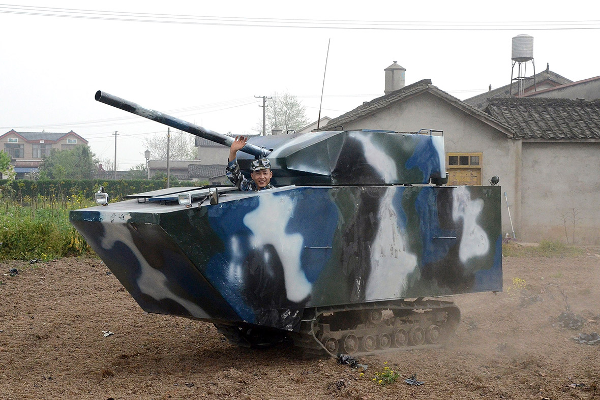Jian Lin, a 31-year-old farmer who used to serve in the Chinese navy, waves in his home-made replica tank during a test-run at a village in Mianzhu, Sichuan province, China