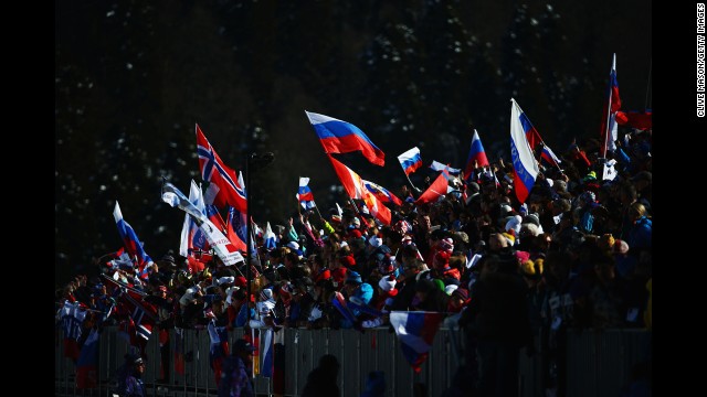 Spectators wave national flags close to the finish line of the women's skiathlon.