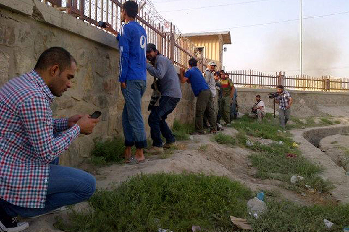 Journalists take cover as fire is exchanged between insurgents and security forces at Kabul's airport