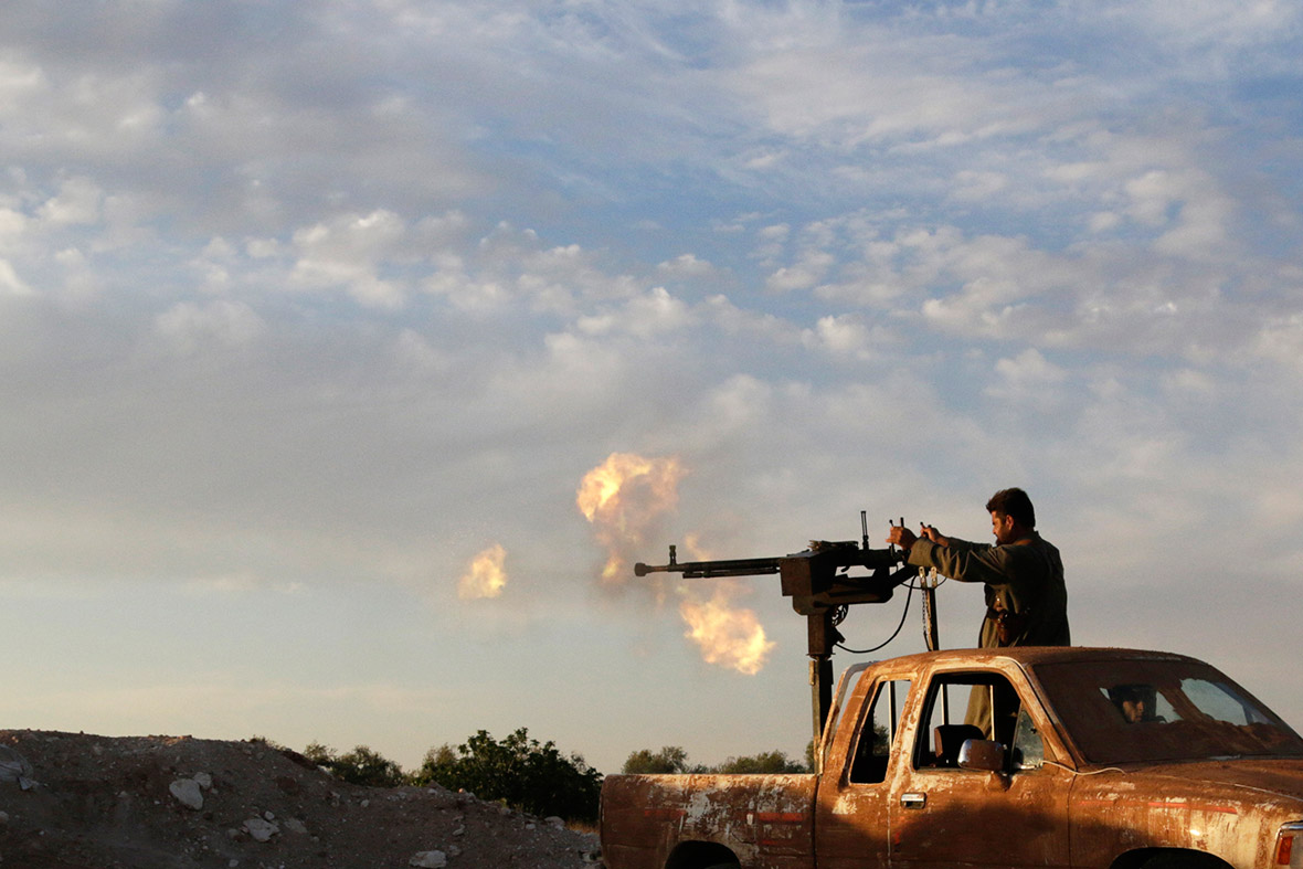 A Free Syrian Army fighter fires an anti-aircraft gun from the back of a pick-up truck in southern Idlib countryside, Syria