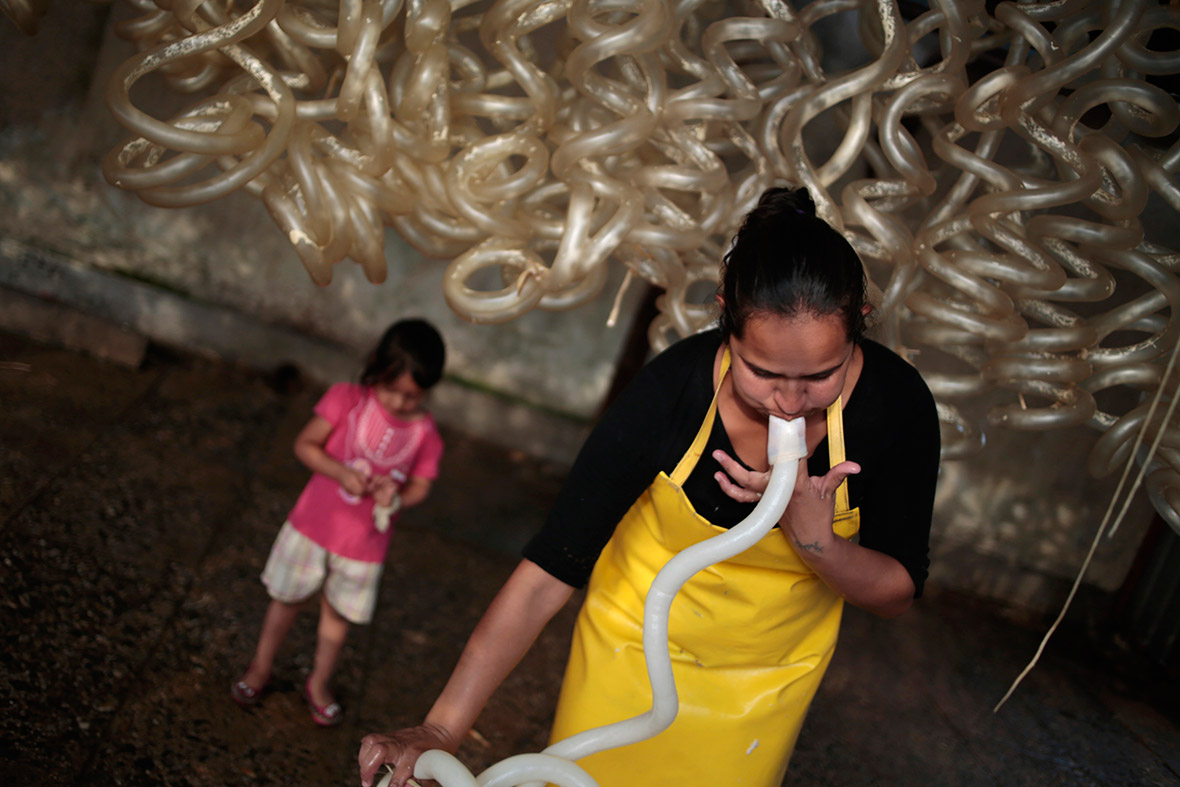 A woman cleans and inflates cow guts which will be used for sausages as her daughter stands behind her, in the 'Cholojeros' zone next to the railway lines in Guatemala City.