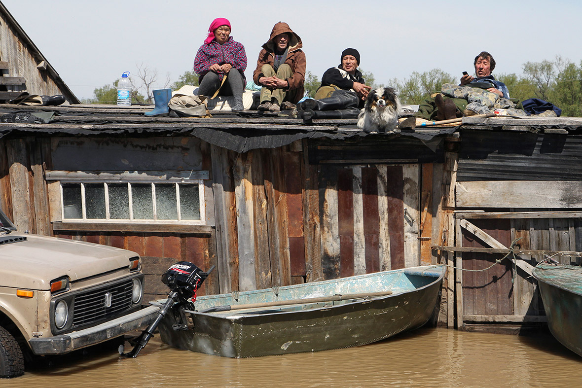 Local residents wait on the roof of houses surrounded by flood water in Ust-Charish in Russia's Altai region