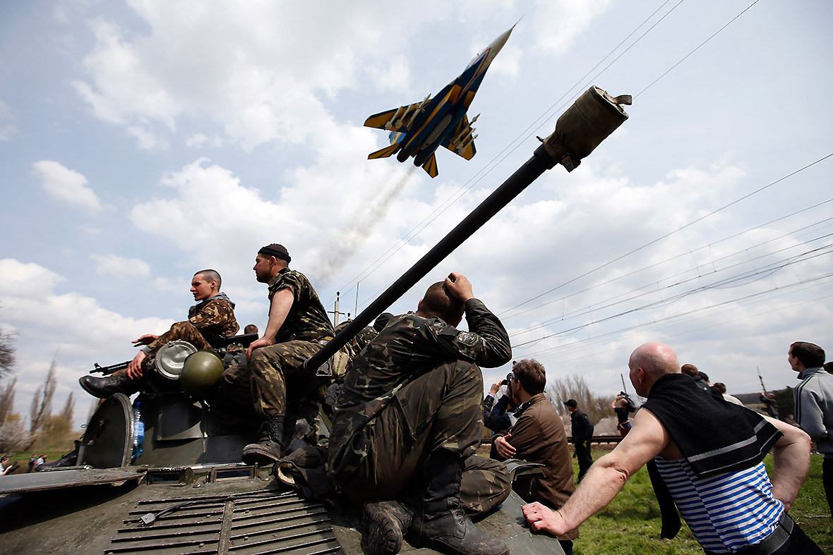 A Ukrainian fighter jet flies overhead as Ukrainian soldiers sit on an armoured personnel carrier in Kramatorsk