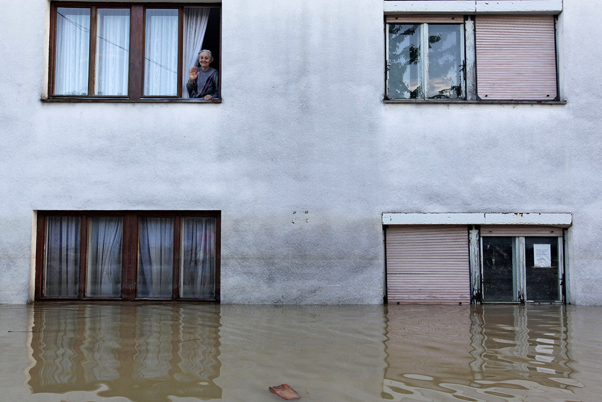 A woman waves from a window during heavy floods in Bosanski Samac, Bosnia