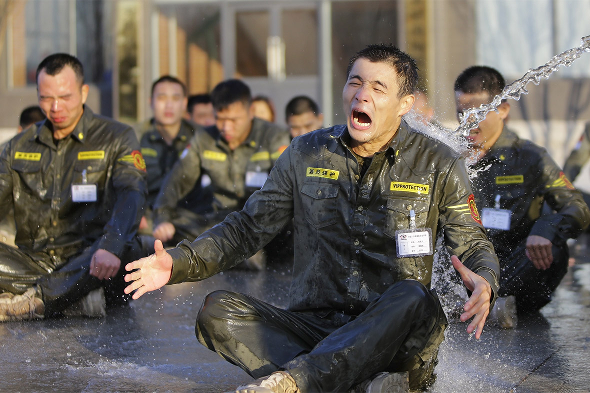 A trainee reacts as he is drenched with water