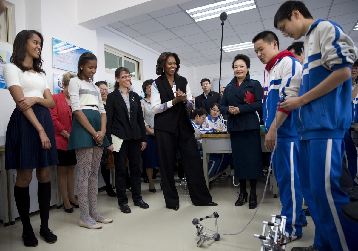 Michelle Obama, her daughters and Peng Liyuan watch students demonstrating a remote-controlled robot, at the Beijing Normal School.