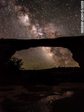 The natural Owachomo Bridge in Utah is silhouetted against the Milky Way and thousands of stars. This photo was taken on a particularly clear night after a storm, and features potholes full of water reflecting the scene, says photographer <a href='http://jwfrank.com' target='_blank'>Jacob Frank</a>. 