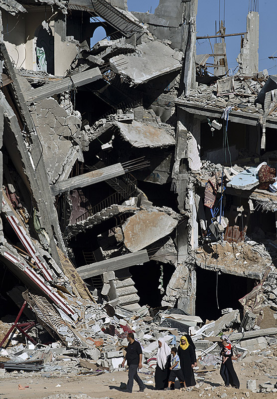 A Palestinian family walks past the collapsed remains of a building that was destroyed in fighting between Hamas militants and Israel during 50 days of fighting in Shejaiya.