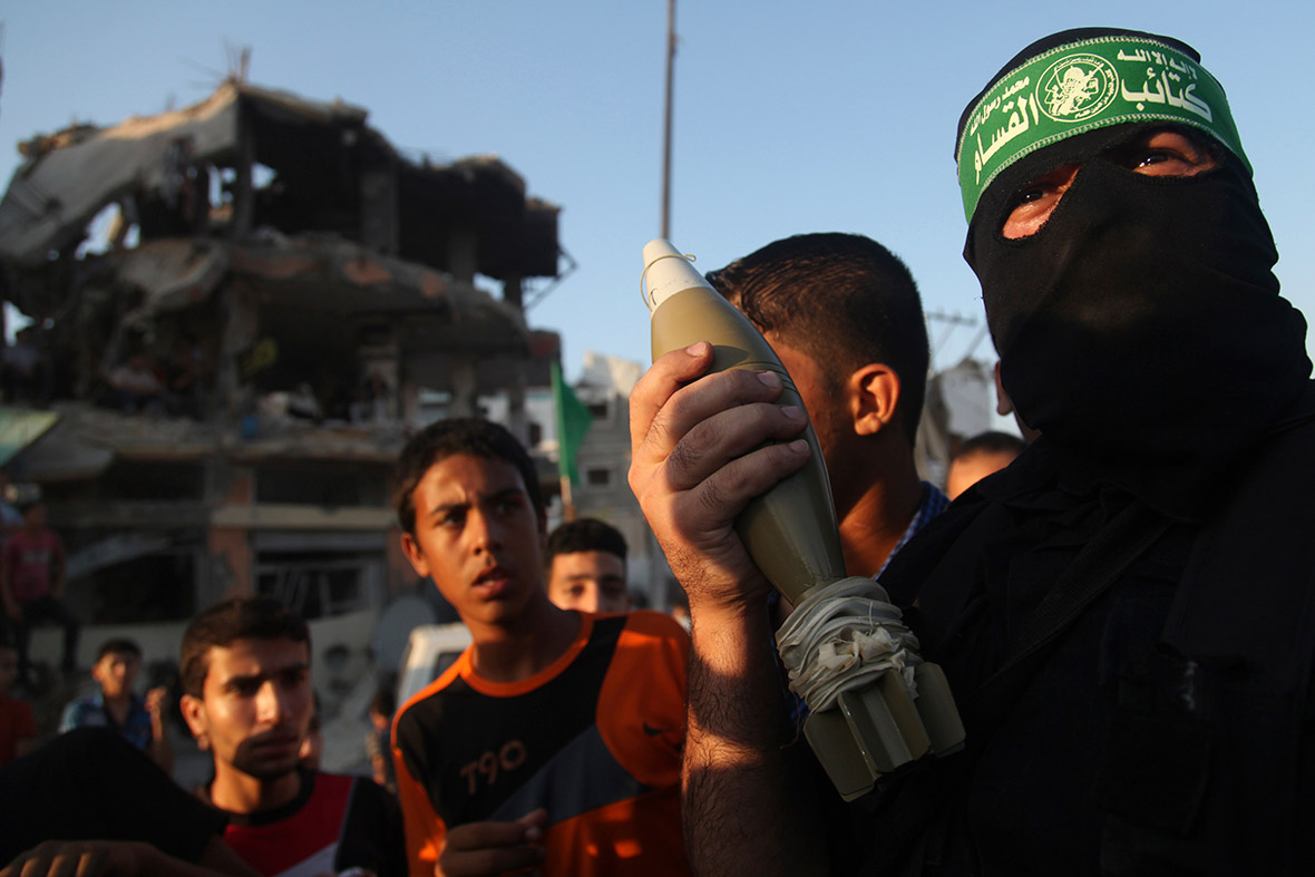 A Hamas militant displays a mortar shell as he celebrates what the militants say was a victory over Israel, in front of a destroyed house in Gaza City.