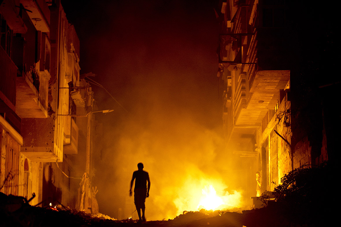 A Palestinian man walks past a fire in a street lined with shattered homes in Shejaiya in Gaza City.