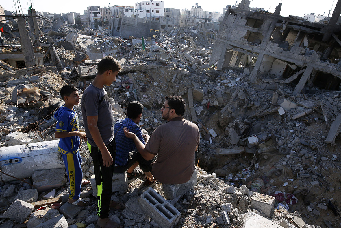 A Palestinian man and three children sit on the rooftop of a partially destroyed home surrounded by bombed buildings in the Shejaiya neighbourhood of Gaza City. Shejaiya was one of the hardest hit areas in the fighting between Hamas militants and Israel.