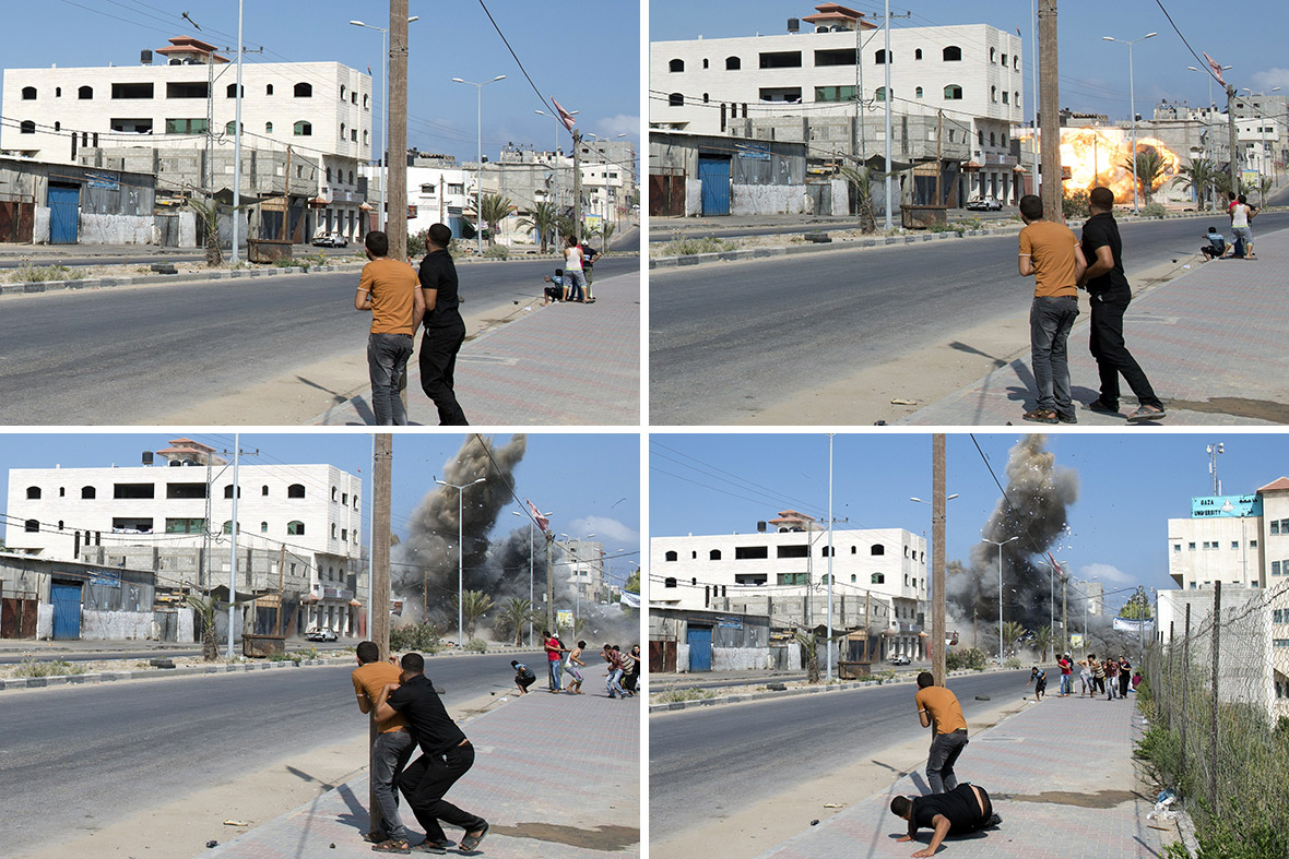 Palestinian men watch and then run as an Israeli bomb drops down and hits a building in Gaza