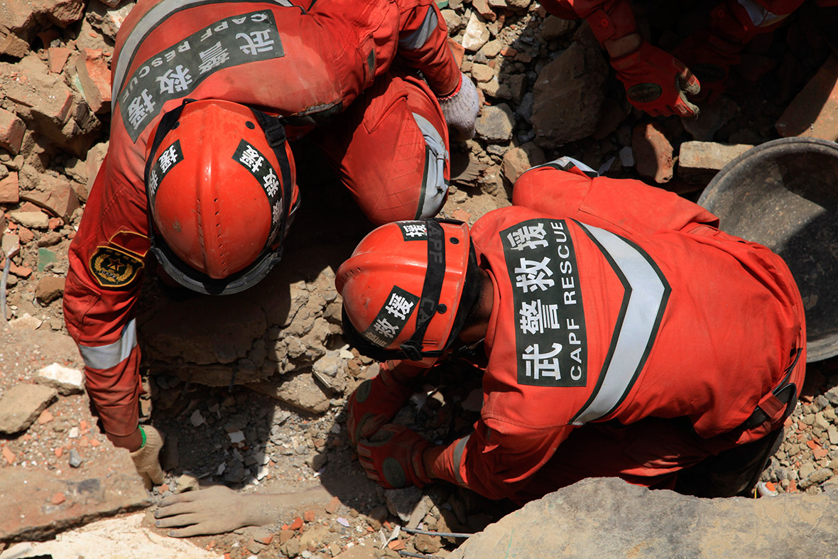 Rescue workers unearth the body of a victim from the debris of collapsed houses in Longtoushan
