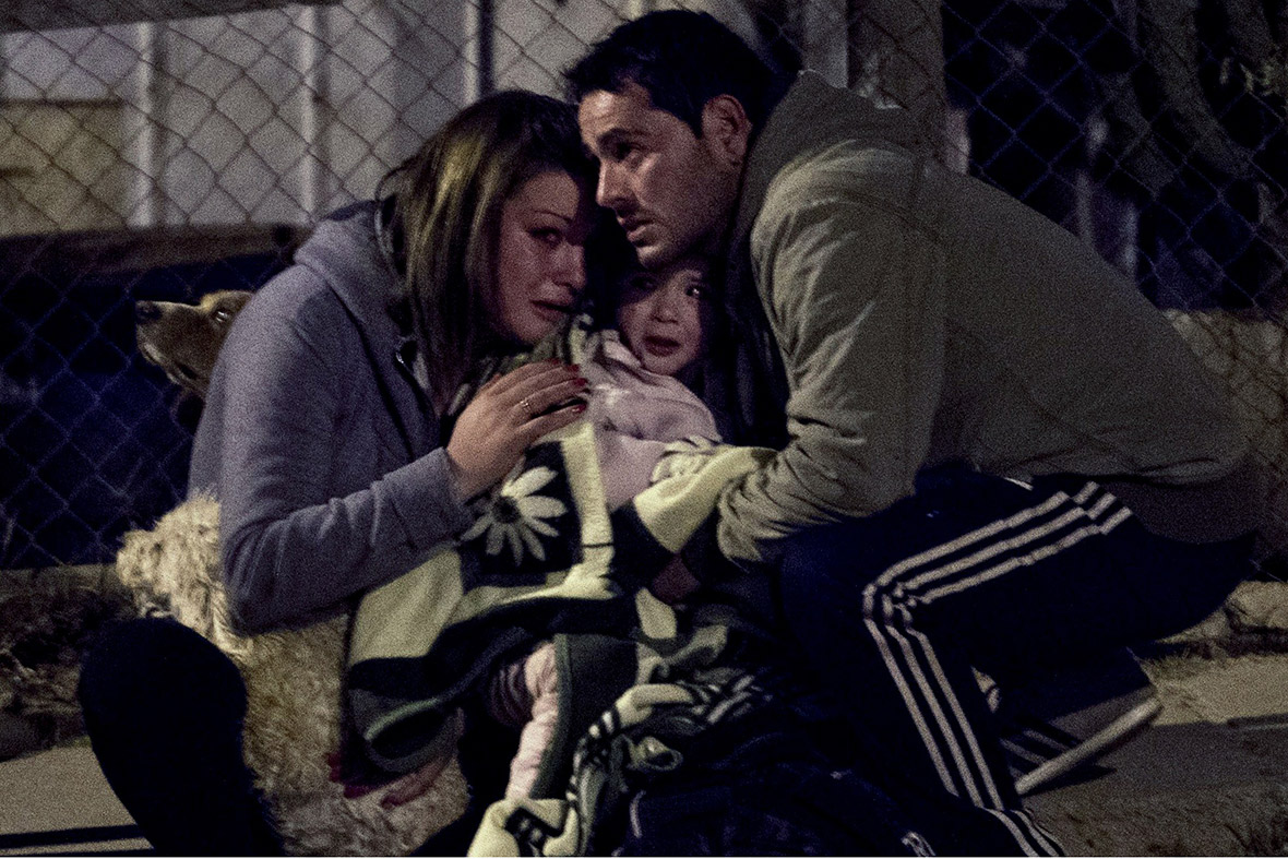 A couple and their baby react in horror after the fire was reignited in part of the city