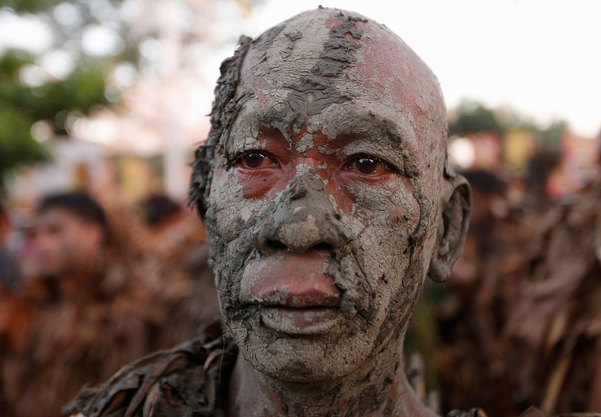 A man covered in mud participates in a religious ritual known locally as 