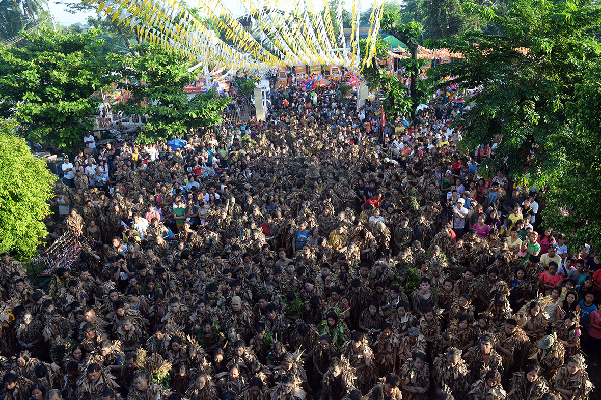 Hundreds of farmers covered in mud and wearing costumes made from banana leaves attend a mass to honour St John the Baptist