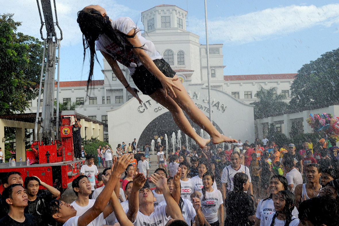 A woman is tossed into the air by friends while the fire brigade drenches her with water in Manila