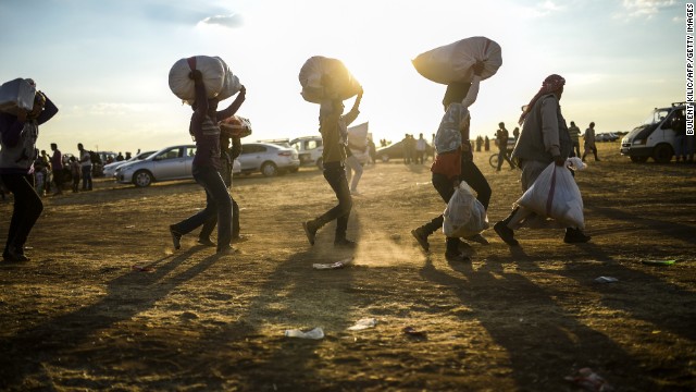 Syrian Kurds carry belongings as they cross the border between Syria and Turkey on September 20.