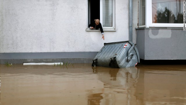 A woman tries to reach a trash container floating in the floodwaters in Obrenovac, Serbia, on May 16.