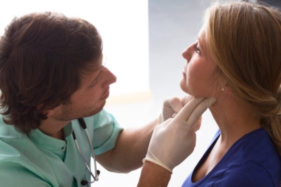 GP examining woman for thyroid