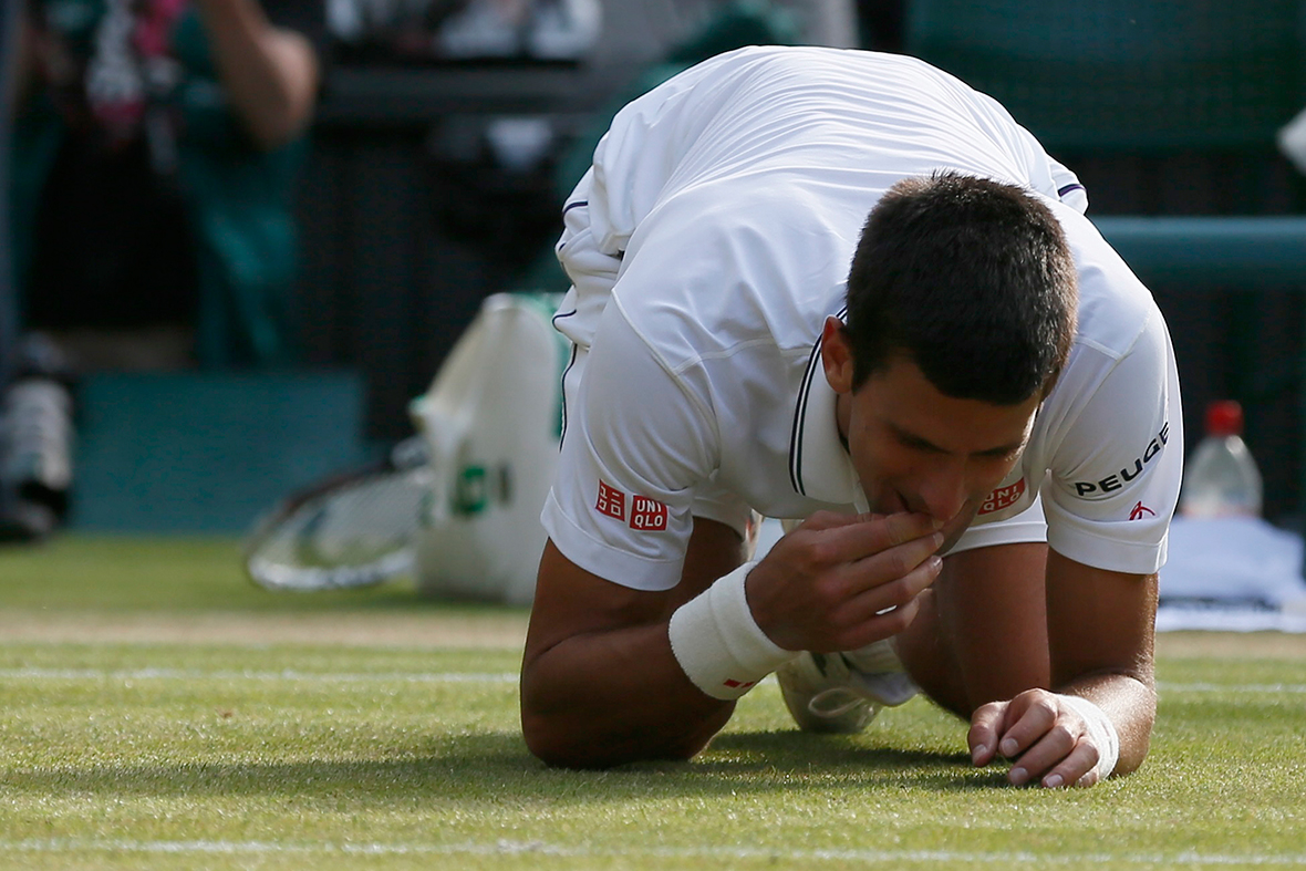 Novak Djokovic of Serbia eats some grass after defeating Roger Federer of Switzerland in their men's singles final tennis match at the Wimbledon Tennis Championships
