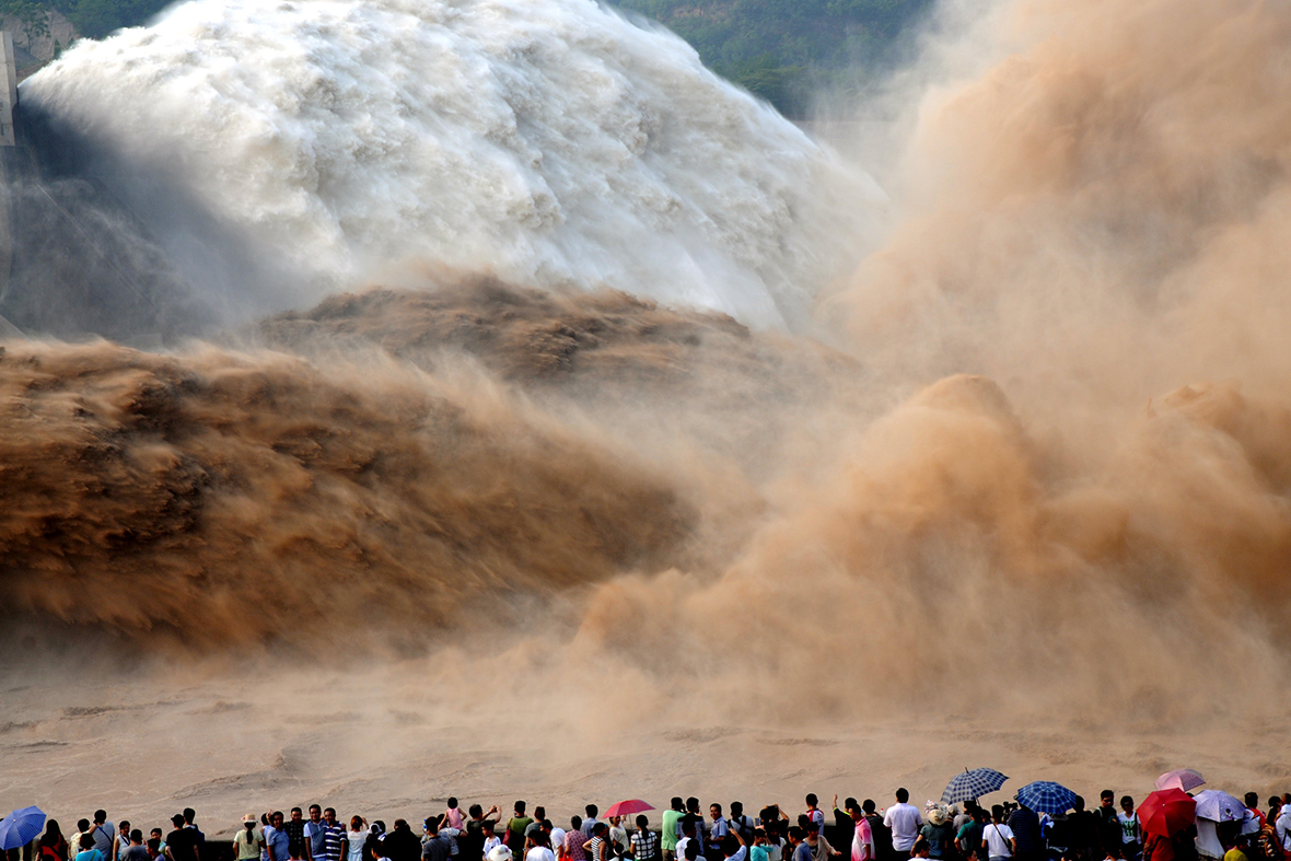 People watch as water gushes from the Xiaolangdi Reservoir on the Yellow River in Jiyuan, Henan province, China, during an operation to clear silt from the water