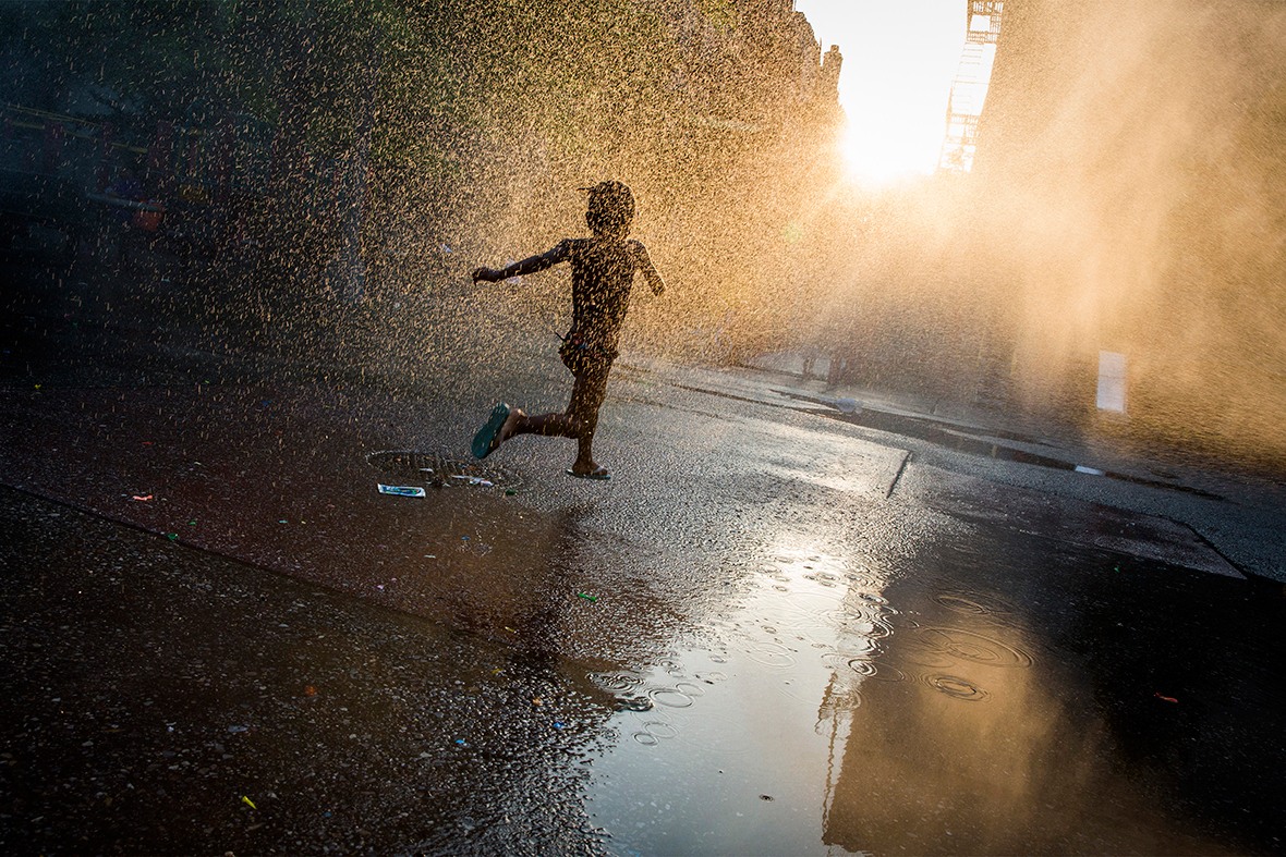 A girl runs through a sprinkler at a playground in the Brooklyn borough of New York