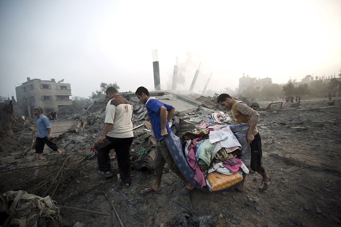 Palestinians collect their belongings from damaged homes after an Israeli missile strike hit Gaza City