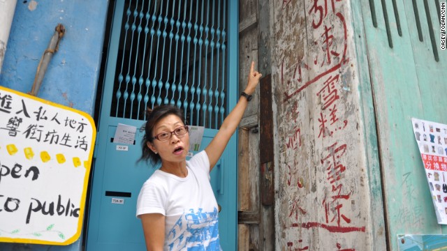 Maria Kwok, a volunteer tour guide who has lived in the neighborhood for almost 30 years, points out old Chinese characters on a wall of the Blue House.