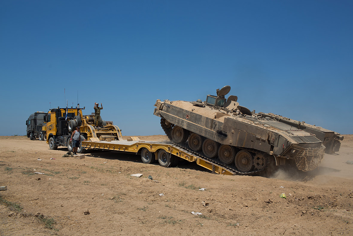 An Israeli military armoured personnel carrier is loaded onto a truck as the army dismantles a deployment area near the Israeli border with the Gaza Strip