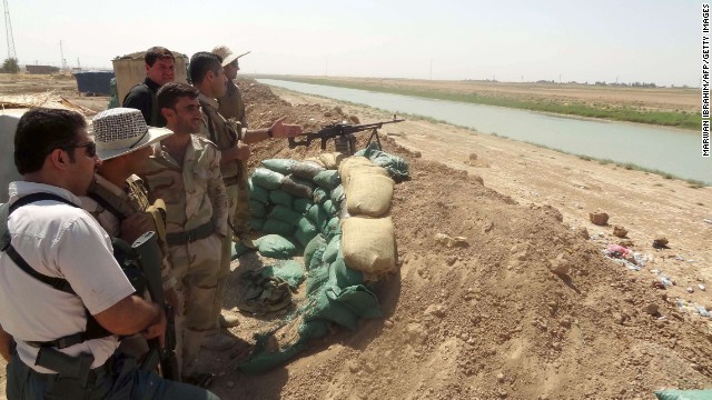 Kurdish Peshmerga fighters stand behind a sand barricade set up close to the village of Bashir on August 17. 