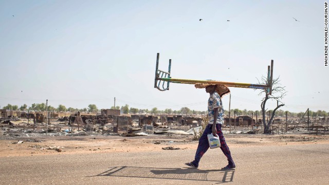 A young man balances a bed on his head as he walks through empty streets and destroyed buildings after government forces retook from rebel forces the provincial capital of Bentiu, in Unity State, South Sudan, on Sunday, January 12.