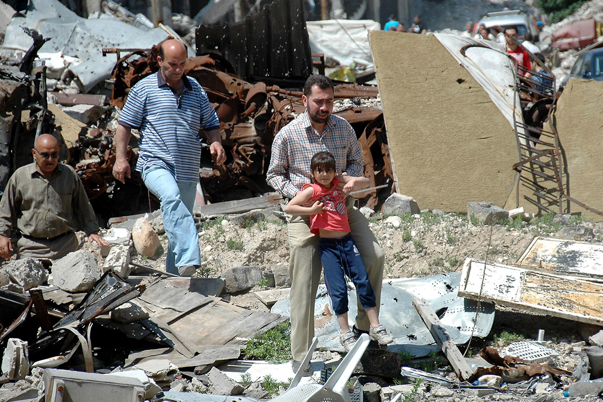 Syrians walk amid debris as they return to their homes