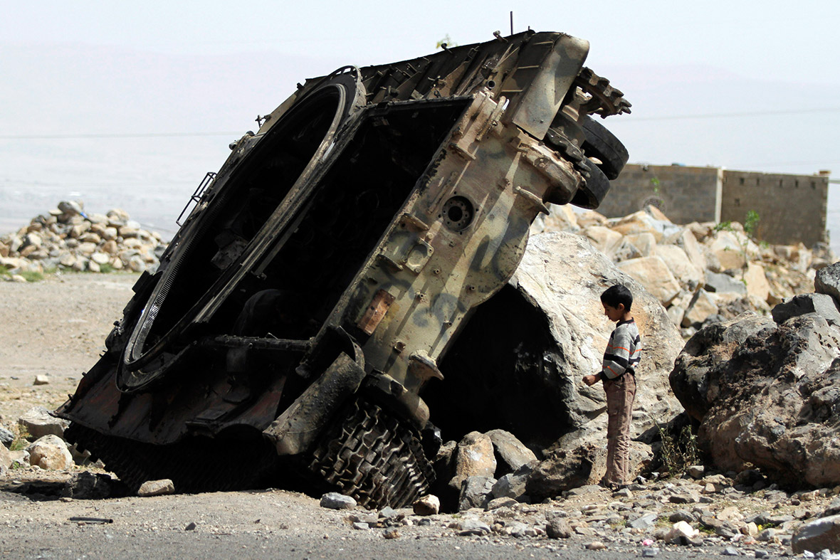 A boy stands near a destroyed armoured vehicle on a road in the northwestern Yemeni province of Omran, where nearly 140 people have died in three days of fighting