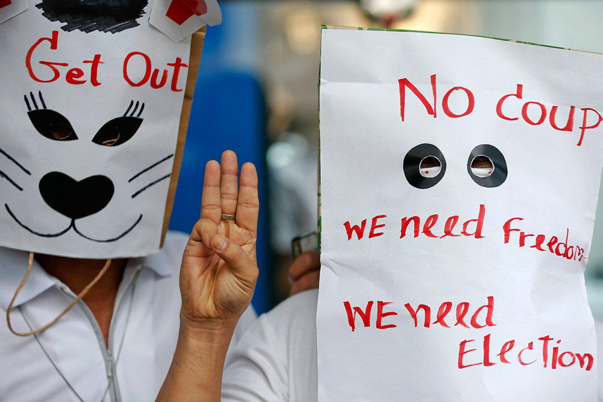 Anti-coup protesters wear paper bags with messages written on them during a protest at a shopping mall in Bangkok