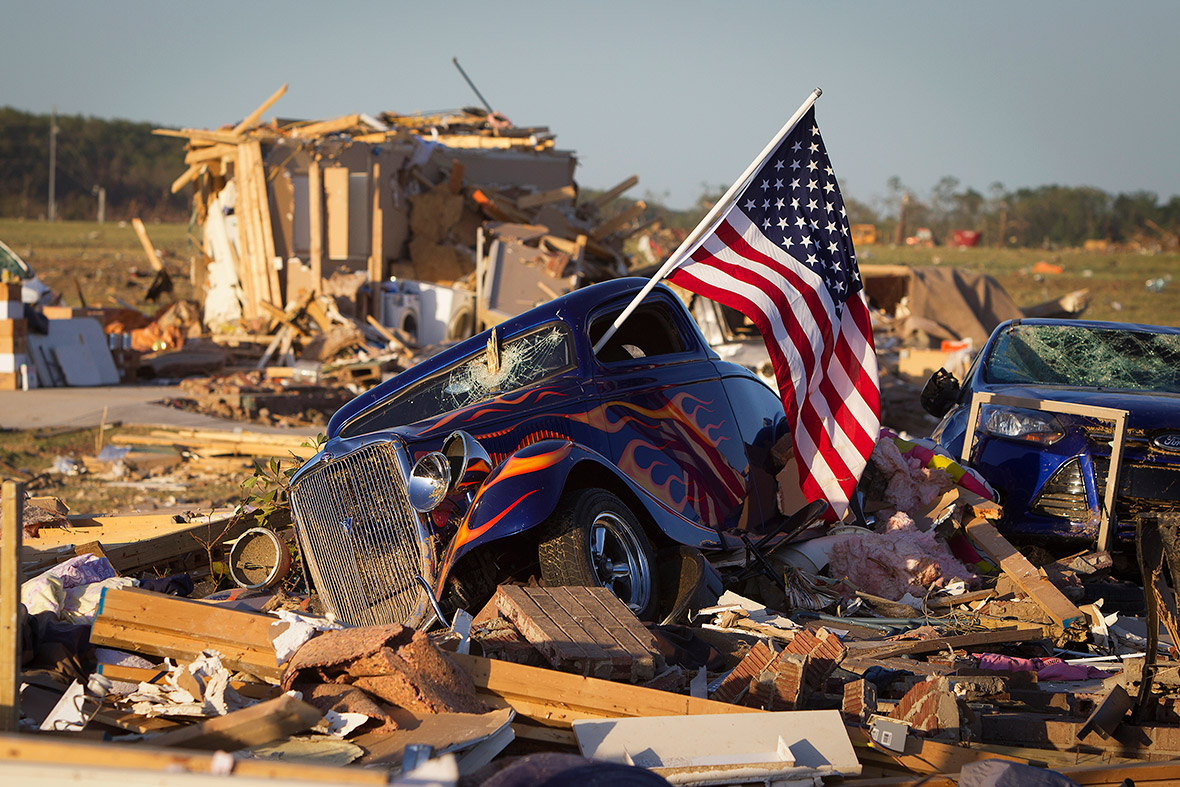 A US flag sticks out the window of a damaged hot rod car in a suburban area near Vilonia, Arkansas