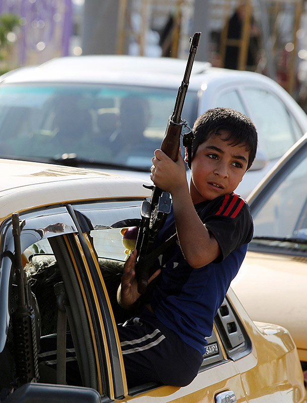 An young boy in a car holds a rifle as people gather in Baghdad to show their readiness to join Iraqi security forces.
