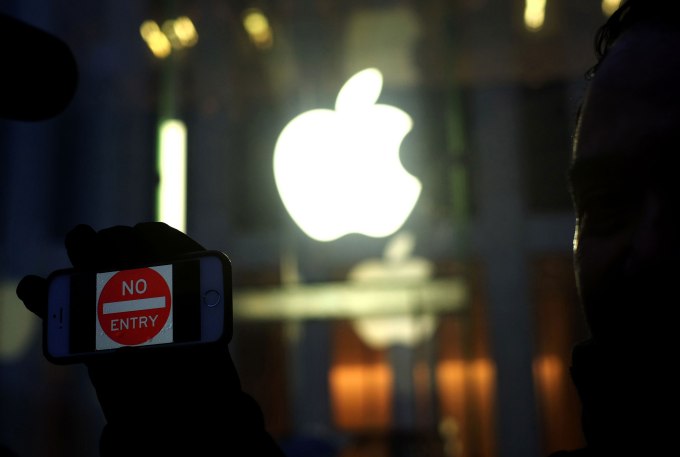 An anti-government protester holds up his iPhone with a sign "No Entry" during a demonstration near the Apple store on Fifth Avenue in New York on February 23, 2016. 
Apple is battling the US government over unlocking devices in at least 10 cases in addition to its high-profile dispute involving the iPhone of one of the San Bernardino attackers, court documents show. Apple has been locked in a legal and public relations battle with the US government in the California case, where the FBI is seeking technical assistance in hacking the iPhone of Syed Farook, a US citizen, who with his Pakistani wife Tashfeen Malik in December gunned down 14 people.
 / AFP / Jewel Samad        (Photo credit should read JEWEL SAMAD/AFP/Getty Images)