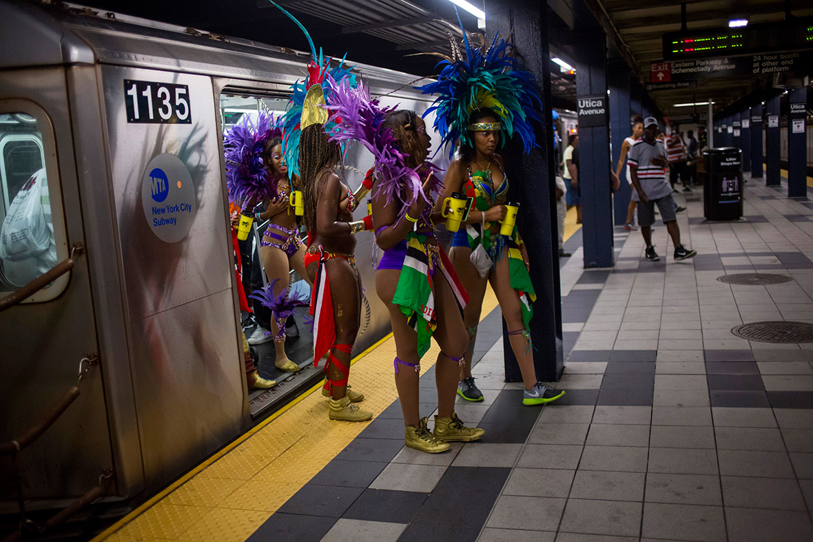 Costumed women walk out of a train as they arrive for the West Indian Day Parade in the Brooklyn borough of New York