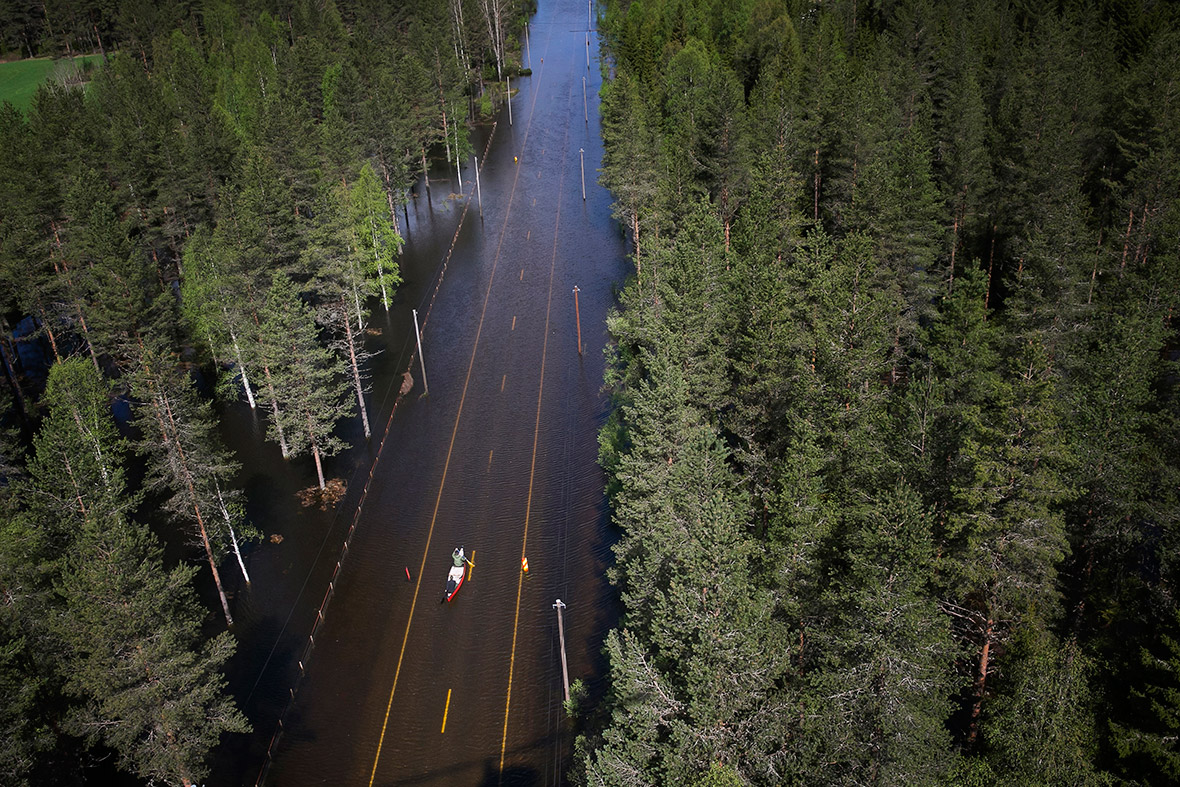 Two men paddle a canoe along a flooded road in Trysil, southeast Norway