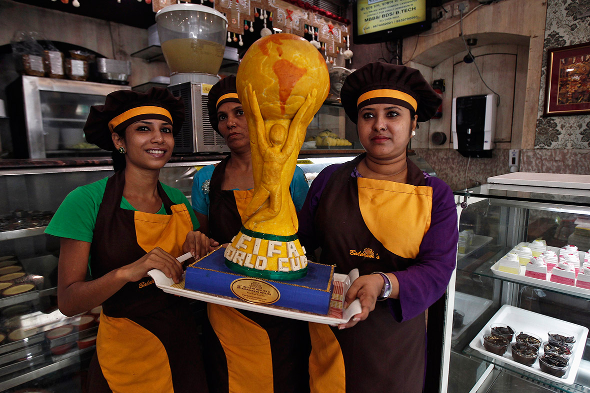 Workers pose with a replica of the World Cup trophy, made from sweets, in a bakery workshop in Calcutta