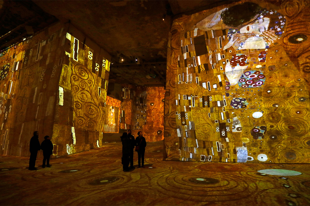 Visitors look at a light show at the exhibition Klimt and Vienna, a Century of Gold and Colours, projected on to the walls of the Carrieres de Lumieres site (Quarries of Lights) in Les Baux-de-Provence, France