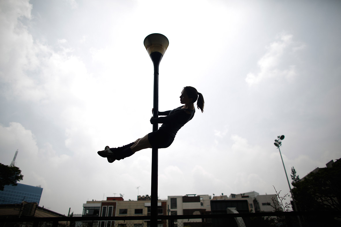 A woman performs a pole-dancing routine on a lamp post in Mexico City during national Urban Pole Dance Day