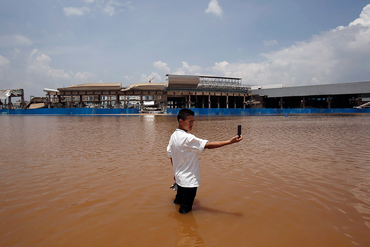 A man takes a picture of himself standing in flood waters at Wujiaba airport in Kunming, Yunnan province, China