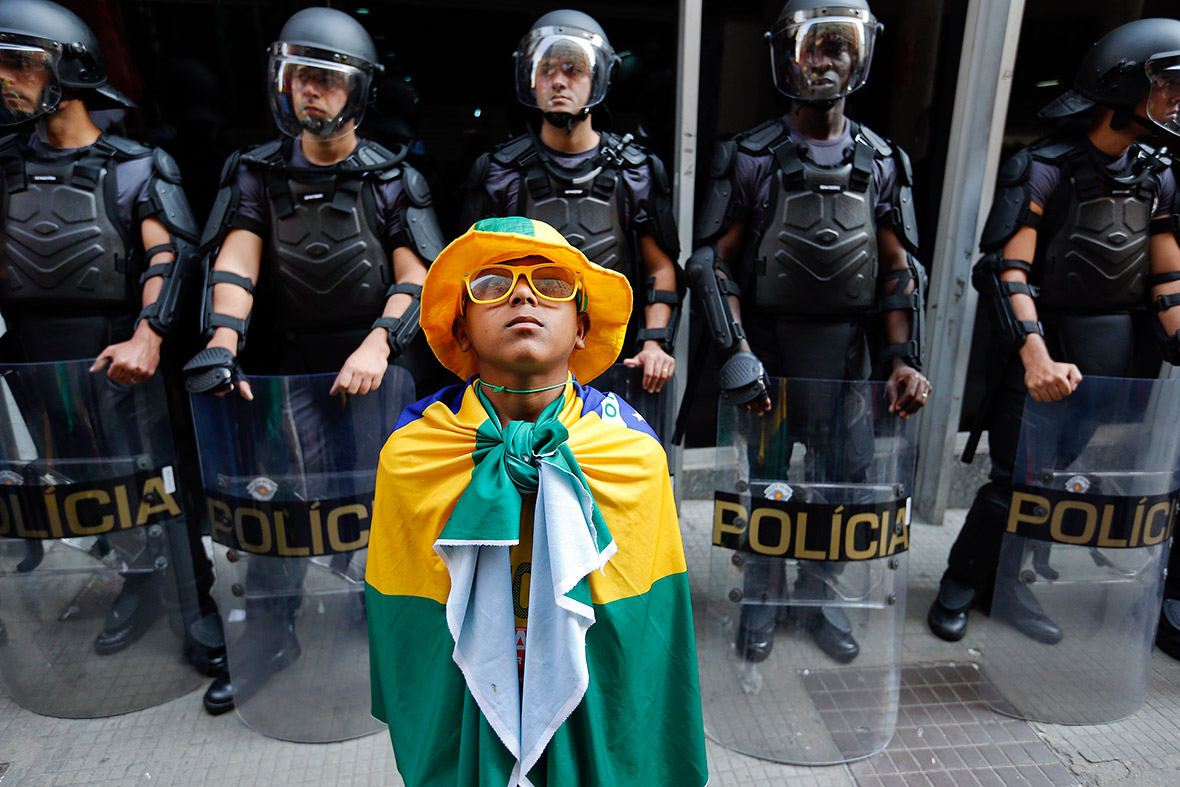 A boy wrapped in Brazilian national flag stands in front of policemen during a protest by metro workers in Sao Paulo