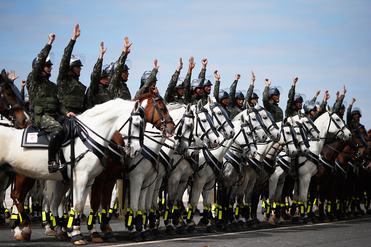 Members of the Brazilian armed forces on horseback salute during a presentation of security equipment that will be used during the 2014 World Cup in Brasilia
