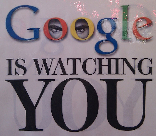 A photograph of a poster (said to be from one of the Google cafeterias) reading "GOOGLE IS WATCHING YOU" with "Google" being the Google logo. The logo also has two eyes in the Os.