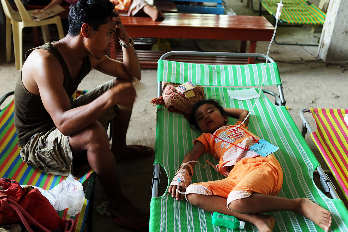 A father seats beside his daughter as she is treated for cholera at a hospital in Alamada, Mindanao, Philippines